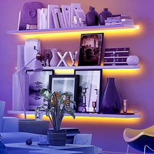 Estanterías con libros iluminadas por tiras LED, creando un ambiente acogedor y moderno en la pared del hogar.